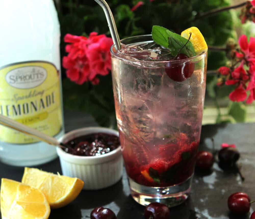 Cherry Lemonade Vodka Spritzer in a tall glass with mint and lemon slice.