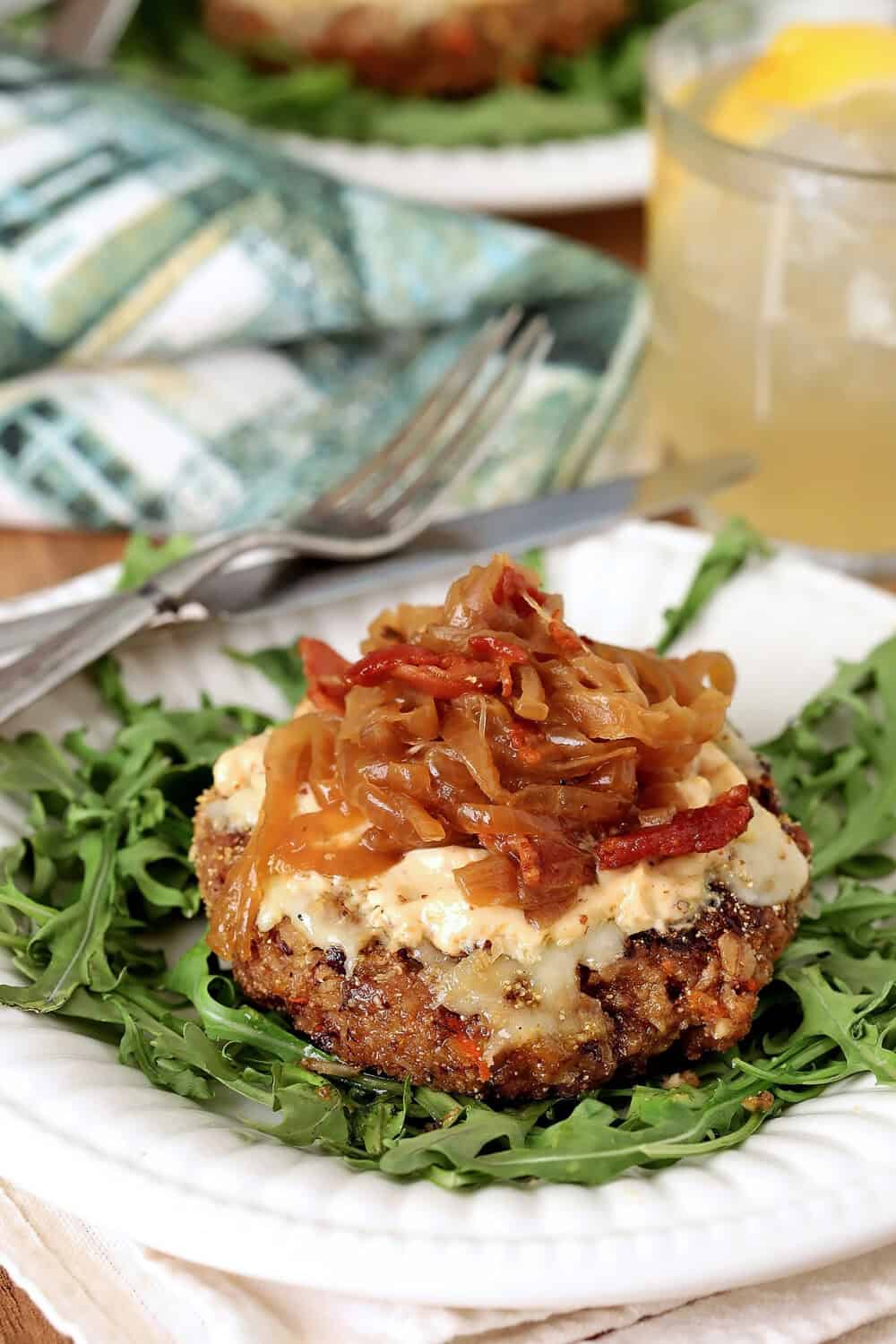 Vegetarian veggie burger with caramelized onions and cheese on a white plate.