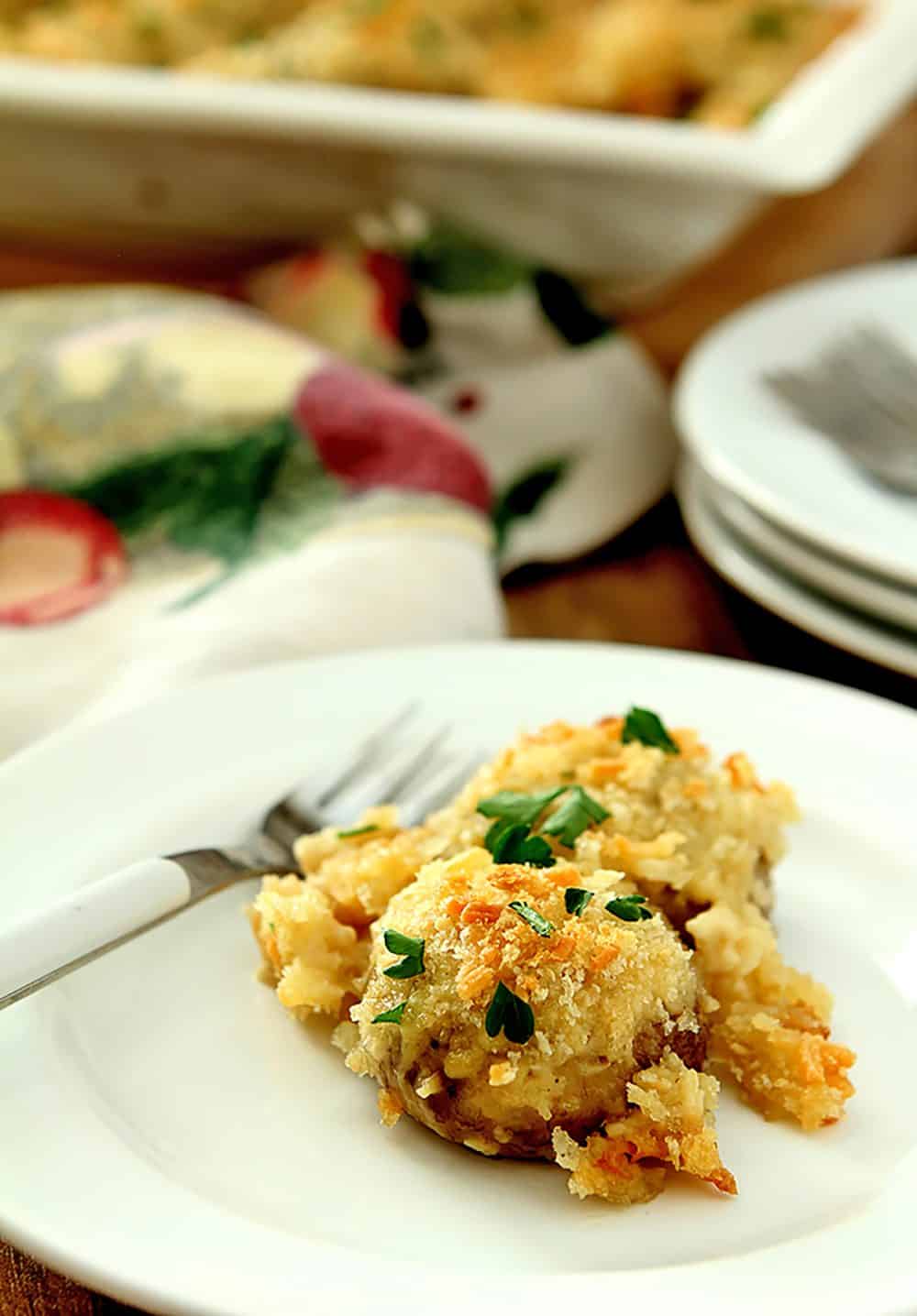 Serving of Baked Mushrooms on a White Plate. Mushrooms are baked in a Parmesan Cream Sauce.