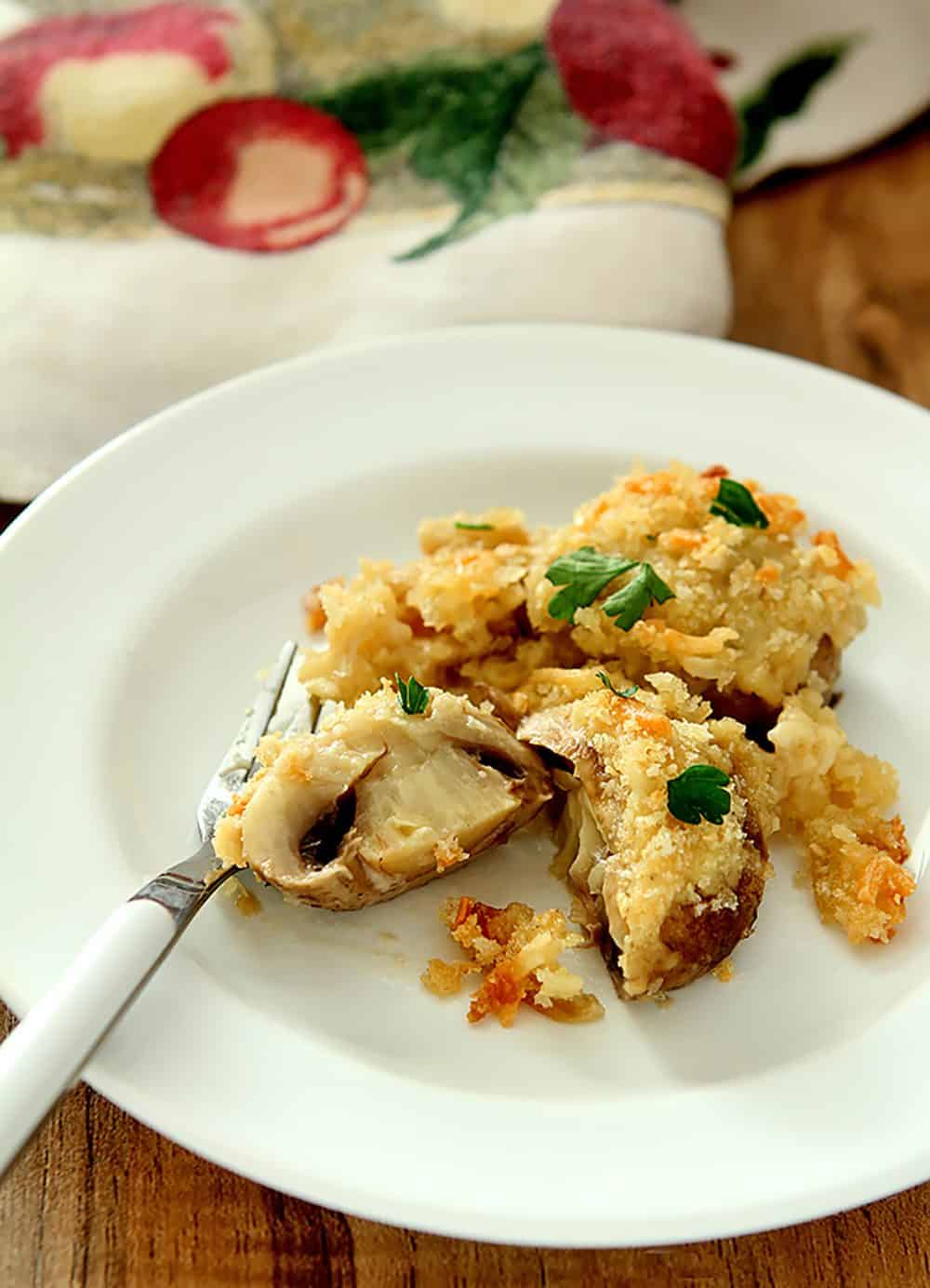 Serving of Baked Mushrooms with Parmesan Cream Sauce, shown on a white plate with one mushroom cut in half.