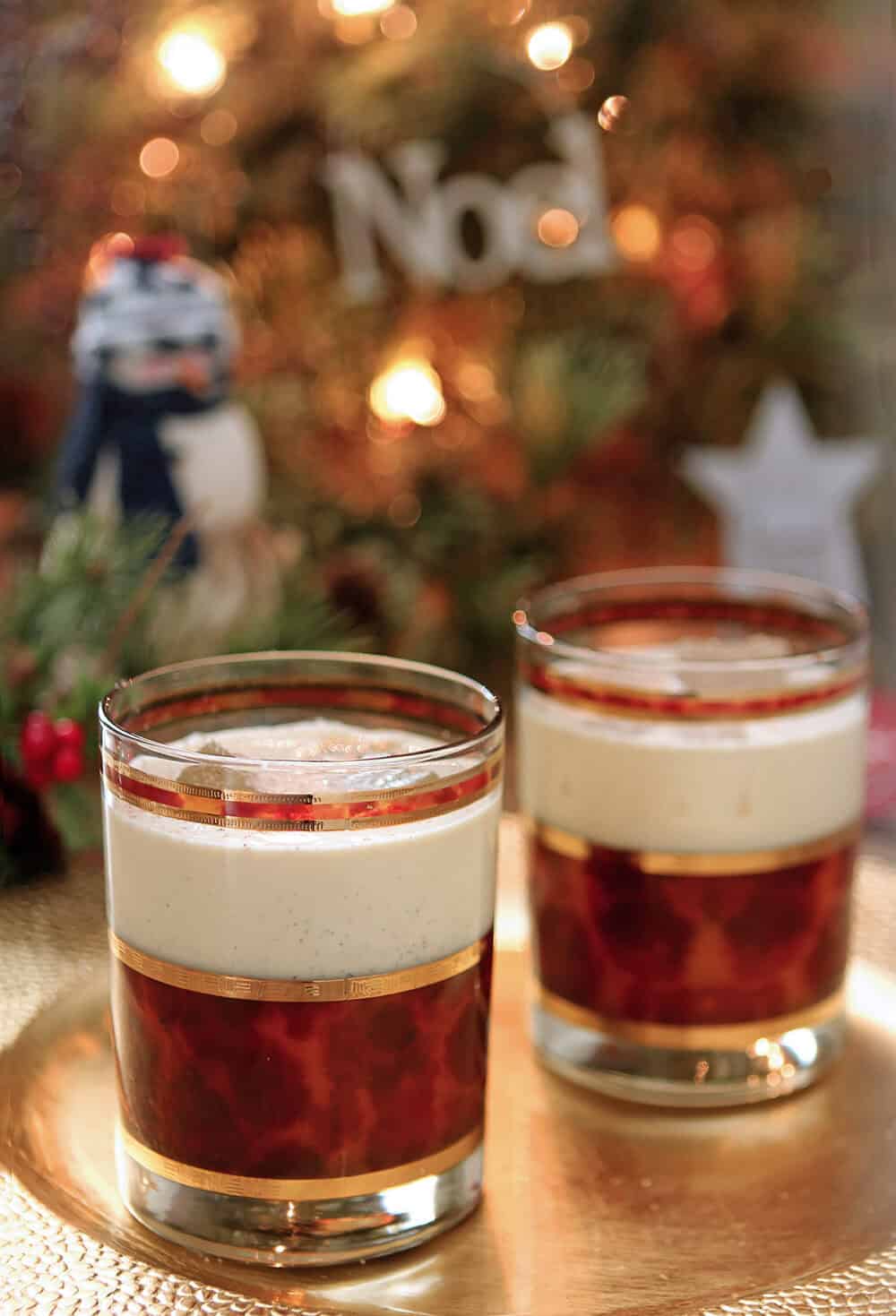 Vanilla Bean Eggnog with Bourbon served in two short glasses decorated with gold and bronze.