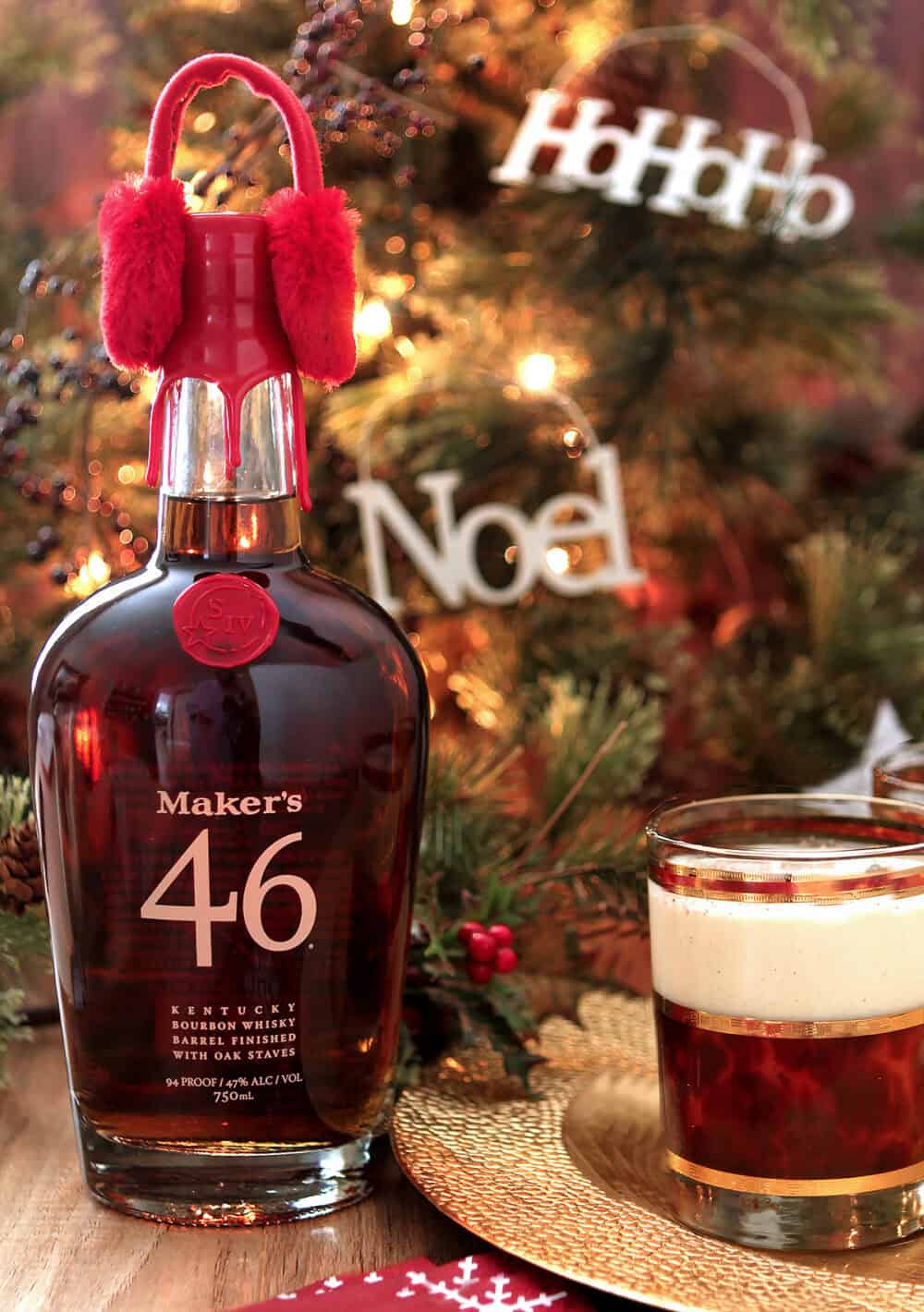 Bottle of Maker's Mark Bourbon with Red Earmuffs next to glass of Vanilla Bean Eggnog with Bourbon.