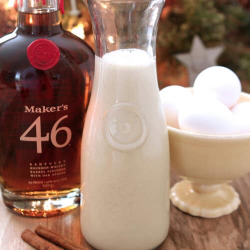 Homemade eggnog with Maker's Mark Bourbon in a tall glass pitcher for serving.