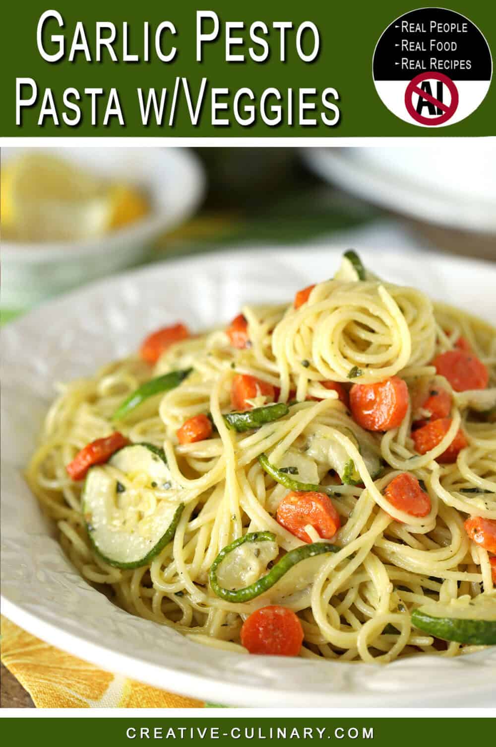 Close-up of garlic pesto pasta with carrots and zucchini on a white plate.