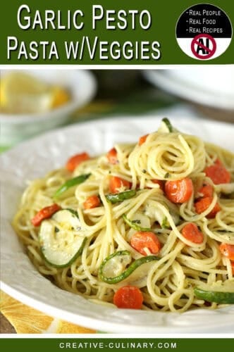 Close-up of garlic pesto pasta with carrots and zucchini on a white plate.