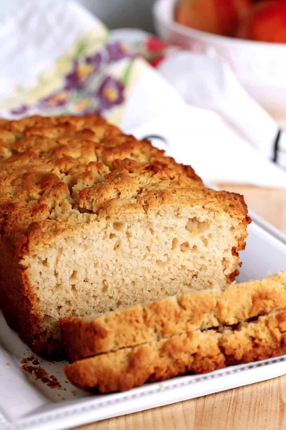 Close-up of honey butter beer bread slice on white plate.