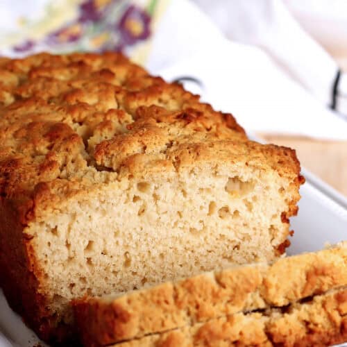 Close-up of honey butter beer bread slice on white plate.