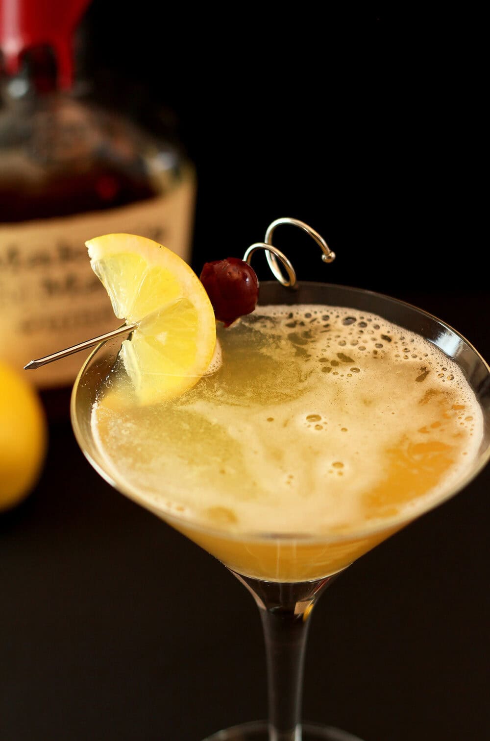 Classic Whiskey Sour Close-up of a whiskey sour cocktail with lemon and cherry garnish.